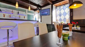 A restaurant interior with a bar area, white bar stools, and a wooden table with pretzel sticks.