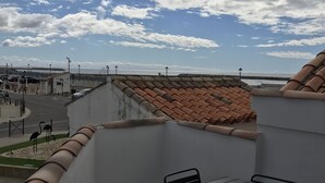 A balcony with a tiled roof overlooking a street and beach. - Luxury seafront apartment 4**** First floor (Saintes-Maries-De-La-Mer)