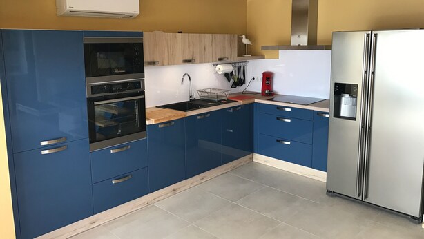 A modern kitchen with blue cabinets, stainless steel appliances, a wooden ceiling, and a built-in water dispenser. - Luxury seafront apartment 4**** First floor (Saintes-Maries-De-La-Mer)