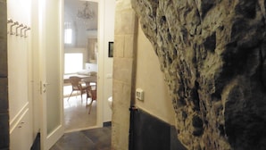 Una habitación con pared de piedra, una puerta que da a un comedor y una araña.
