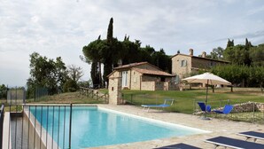 A swimming pool with a stone deck, a small stone building, and a grassy area with trees and a fence. - Spacious villa with swimming pool in stunning scenery and picturesque villages (Perugia)