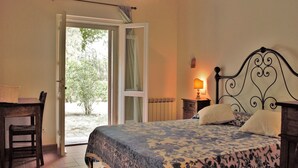 A bedroom with a bed, a desk, and a chair. There is a window with a view of greenery outside. - Spacious villa with swimming pool in stunning scenery and picturesque villages (Perugia)