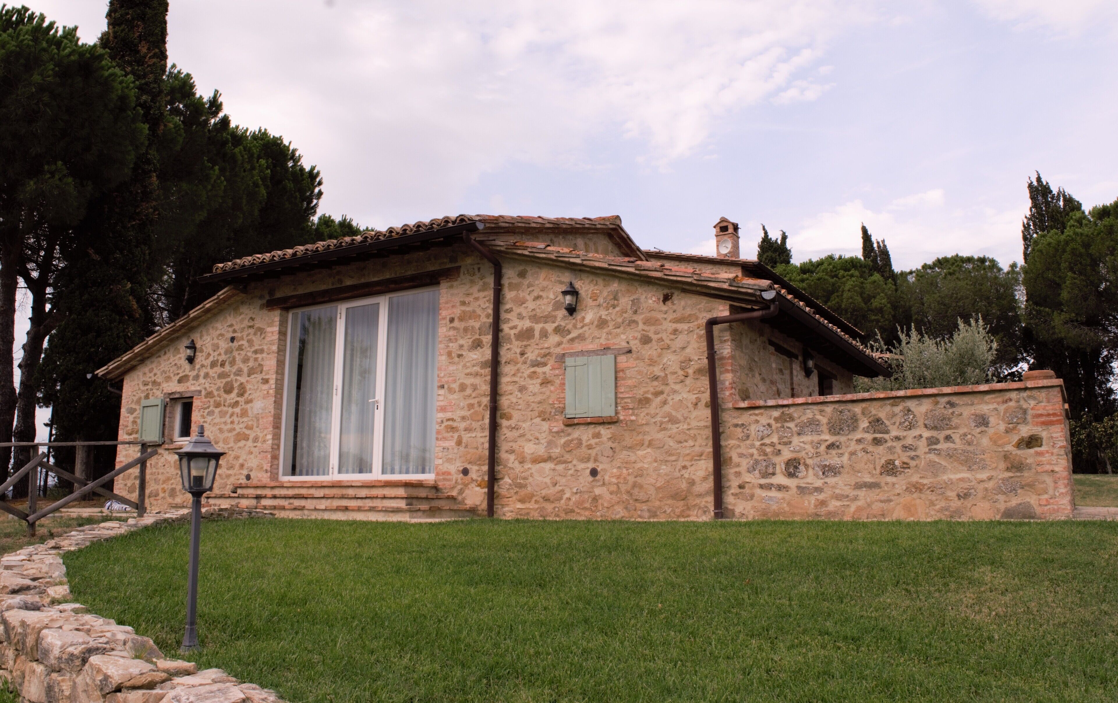 Una casa in pietra con tetto in tegole, un'ampia finestra e un portone piccolo.