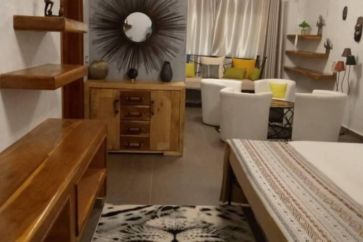 Ein Schlafzimmer mit einem Bett, einer Holzkommode, einem Spiegel und einem gemusterten Teppich.