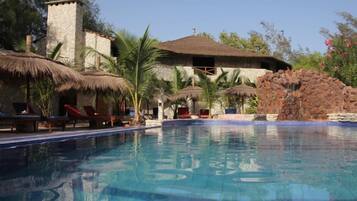 Een buitenzwembad, parasols bij het zwembad en ligstoelen