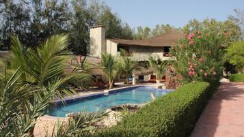 Een buitenzwembad, parasols bij het zwembad en ligstoelen