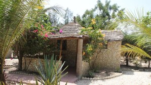 A small stone building with a thatched roof, surrounded by tropical plants and flowers. - Le Calao du Lac Rose (Niaga)