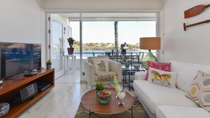Una sala de estar moderna con televisor, sofá, mesa de centro y un balcón con vistas.