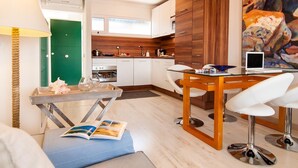 Una cocina moderna con armarios blancos, un revestimiento de pared de madera y un comedor con mesa y sillas.
