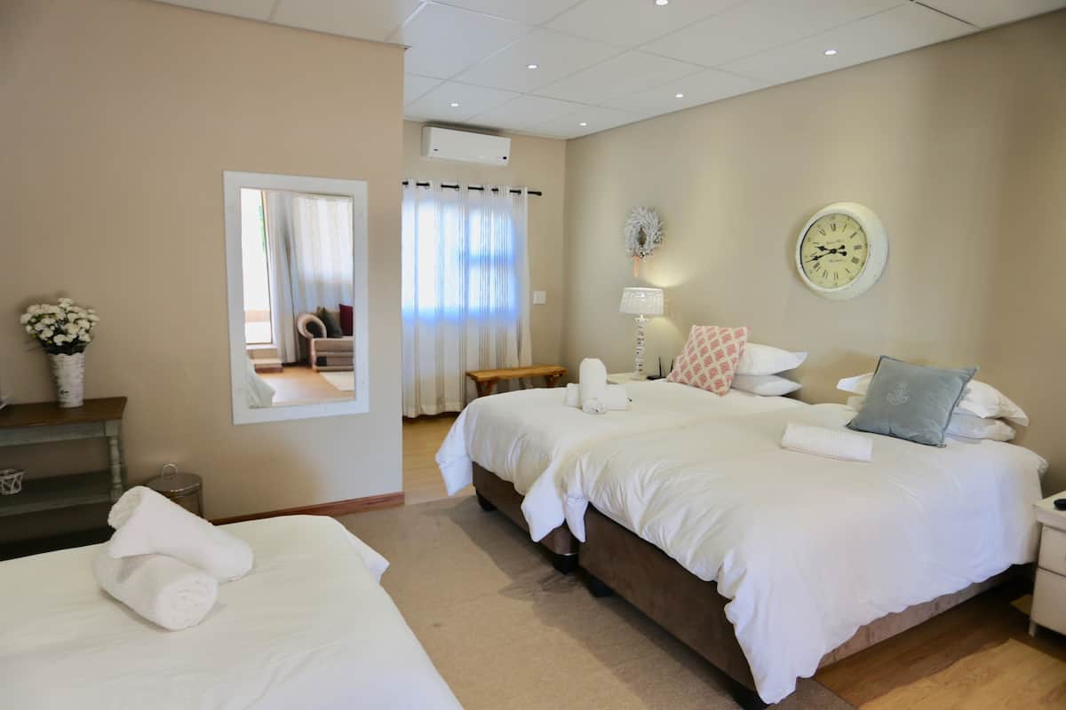 Une chambre d’hôtel avec deux lits, un grand miroir, une horloge et une fenêtre avec des rideaux.