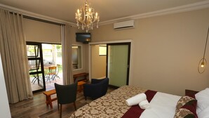 Une chambre d’hôtel avec un lit, un bureau, une chaise et une vue sur la terrasse extérieure.