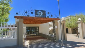 Une entrée fermée par un portail, sur laquelle est apposée une enseigne indiquant : « BGM Boutique, maison d’hôtes pour couples ».