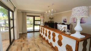 Un espace d’accueil doté d’un comptoir en bois, d’un lustre et d’une grande fenêtre agrémentée de rideaux.