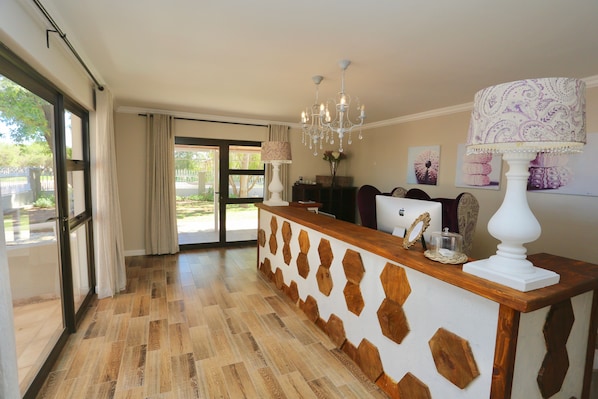 A reception area with a wooden reception desk, a chandelier, and a large window with curtains.