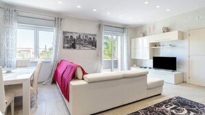 A modern living room with a sofa, dining table, and TV. - Villa Joel with splendid swimming pool in the heart of Fontane Bianche (Fontane Bianche)