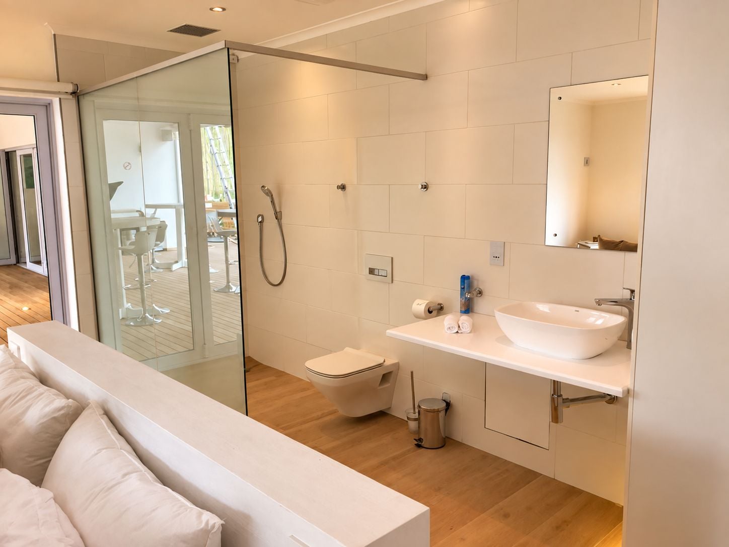 Et moderne badeværelse med en glasbrusekabine, en hvid vask og et toilet.