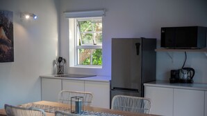 A compact kitchen with a dining area, a refrigerator, a microwave, and a coffee maker. - theLAB Franschhoek (Franschhoek)
