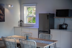Una cocina compacta con comedor, refrigerador, microondas y cafetera.