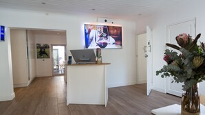 A modern interior with a wooden floor, a laptop on a small table, a TV mounted on the wall, and a door leading to another room. - theLAB Franschhoek (Franschhoek)
