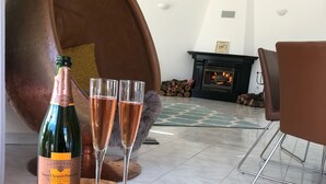 A room with a large copper chair, a fireplace, and a wooden table with a bottle of champagne and two glasses. - 4 Bedroom Deluxe Villa, Private Pool, Mature Grounds, Hot Tub*, Putting Green + (Quarteira)