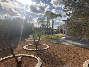 Un jardin aménagé avec des motifs circulaires en gravier, une pergola et un espace piscine.