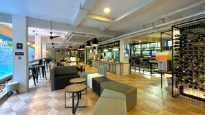 A modern bar area with seating, a wine display, and a view of the pool. - ISTY Hotel (Chiang Mai)