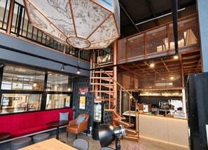 A modern interior with a staircase, seating area, and a bar. - ISTY Hotel (Chiang Mai)