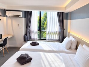Habitació d'hotel amb dos llits, una taula de treball i una finestra amb cortines.