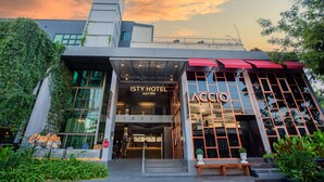 The ISTY HOTEL entrance with a glass facade, a red awning, and a bench outside. - ISTY Hotel (Chiang Mai)