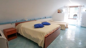 Ein Schlafzimmer mit zwei Betten, einem Nachttisch, einem kleinen Tisch und einem Fenster mit Vorhängen.