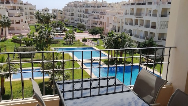 Un balcó amb vista a una piscina i edificis circumdants.