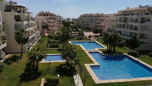 Un complex turístic amb diversos edificis, una piscina central i zones verdes ben cuidades.