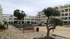 Un pati amb un camí de pedra, una banca i un parc infantil.