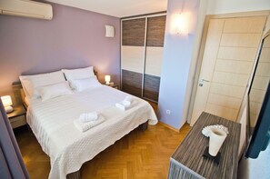 Ein ordentlich bezogenes Bett mit weißen Leinen und Handtüchern, eine Nachttischlampe und ein Holzboden.