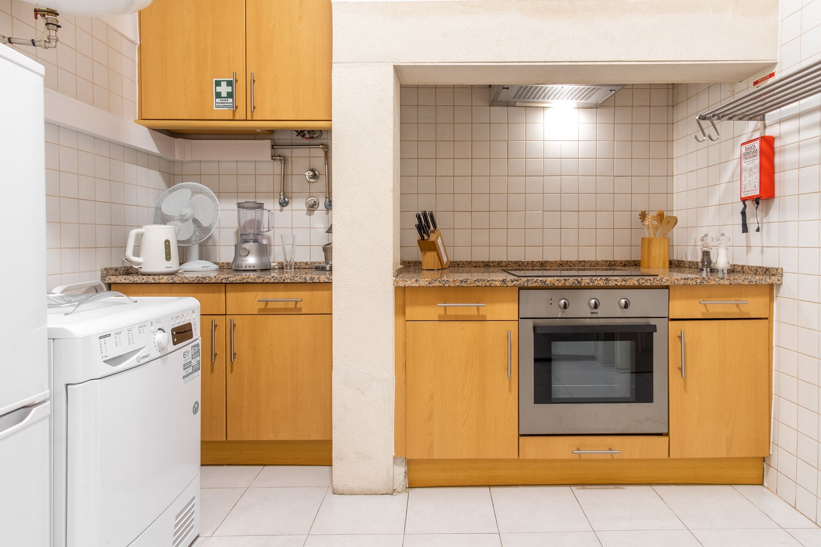 A kitchen with wooden cabinets, a stainless steel oven, a coffee maker, and a washing machine.