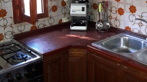 Une cuisine avec des meubles en bois, une cuisinière à gaz, une machine à café et un évier.