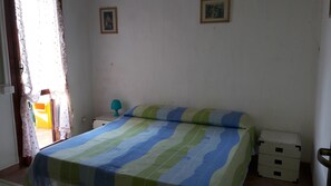Un dormitorio con cama, mesita de noche, lámpara y cómoda.
