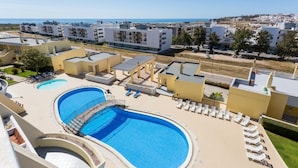 Un complexe hôtelier doté d’une grande piscine, de chaises longues et offrant une vue sur la mer.