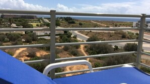 Un balcon offrant une vue sur un paysage côtier, avec des routes et des bâtiments.