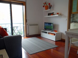 Relax in this stylish living room with a flat-screen TV, comfortable sofa, and dining table.