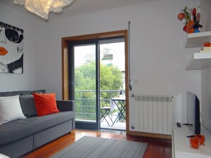 Relax in this stylish living room with a sofa, flat-screen TV, and balcony access.