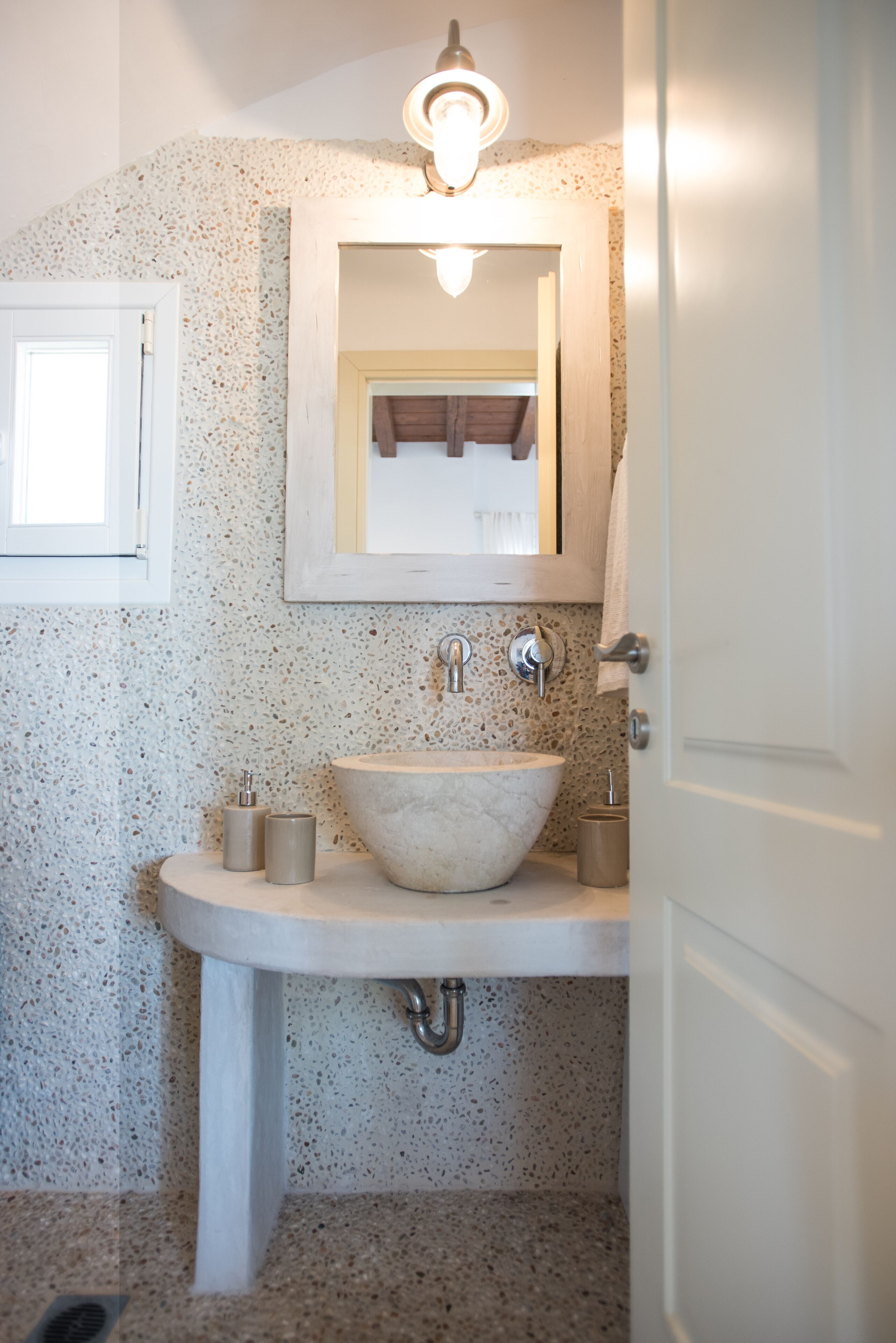 A bathroom with a freestanding sink, a mirror, and a light fixture above the mirror.