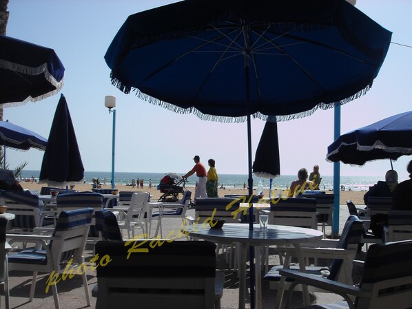 A beachside cafe with outdoor seating and umbrellas.