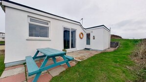 A white building with a picnic table, a lifebuoy, and a small sign. - D02 Greendune (D2), Riviere Towans (Hayle)