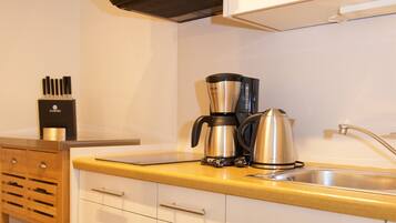 Una cocina moderna con armarios blancos, una cafetera de acero inoxidable y un hervidor sobre la encimera.