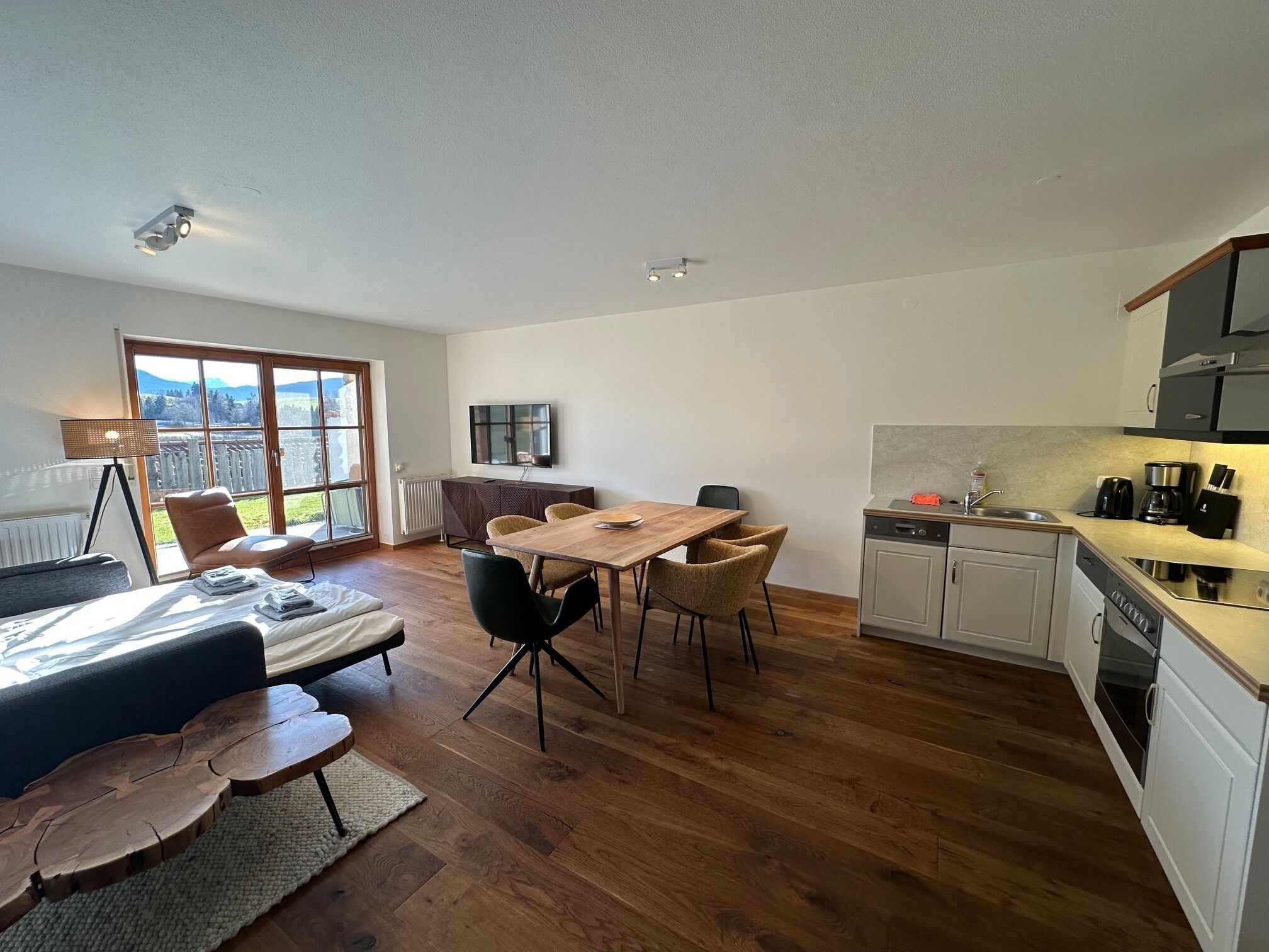 A modern living space with a dining area, kitchen, and a large window offering a view of the outdoors.