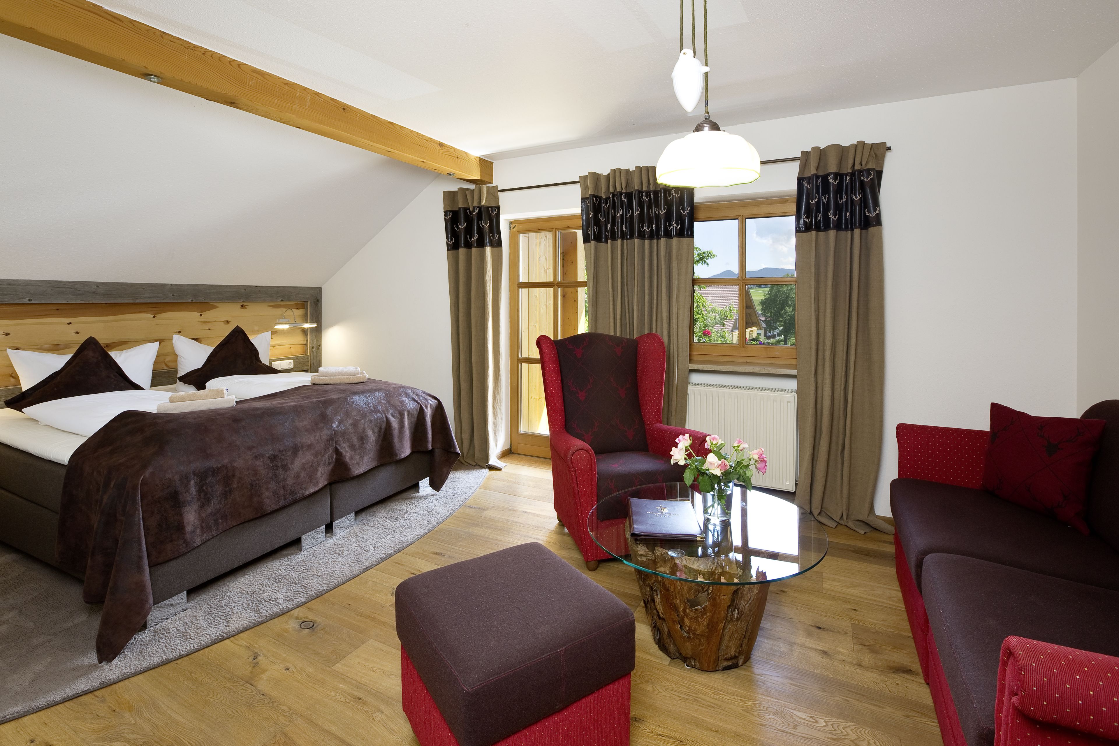 Een slaapkamer met een bed, een rode fauteuil, een glazen salontafel en een rode bank.