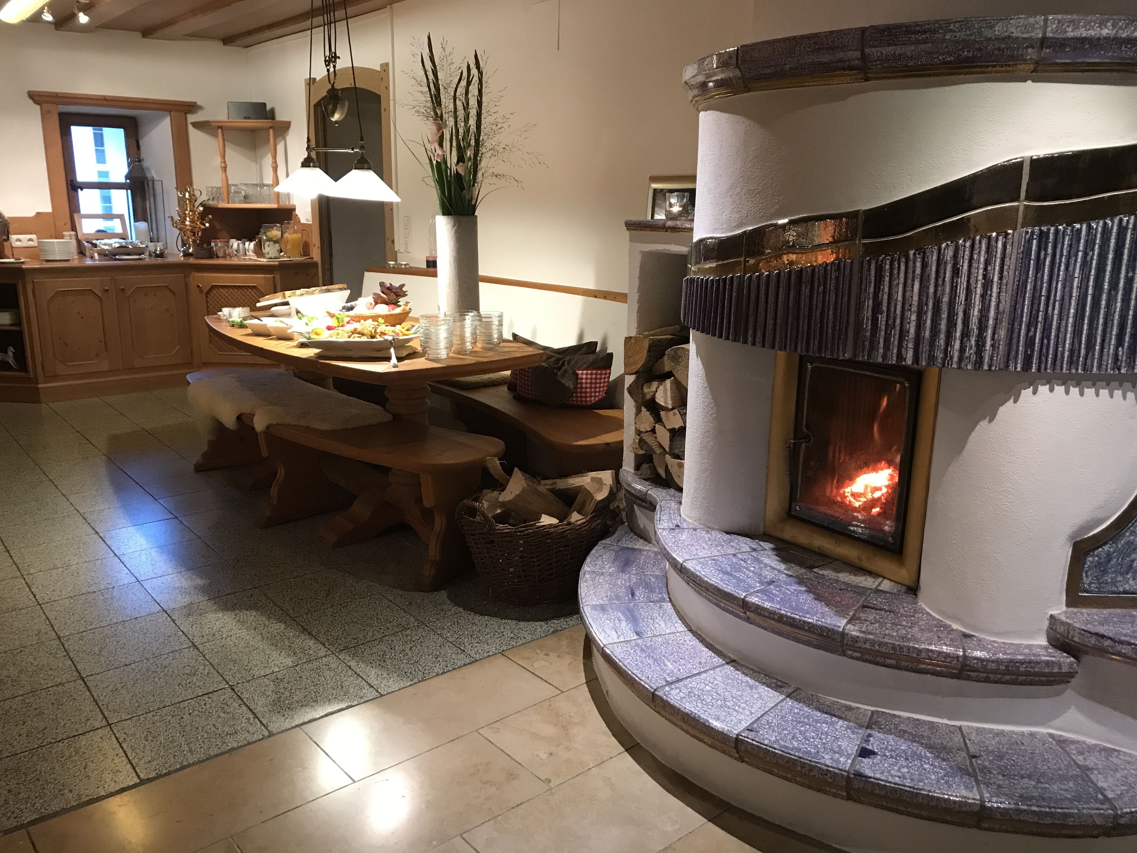 A cozy kitchen with a stone fireplace, wooden furniture, and a dining area.