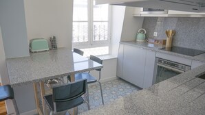 Une cuisine dotée d’un plan de travail en granit, d’un grille-pain, d’une bouilloire et d’une fenêtre donnant sur une clôture.