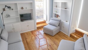 Un salon avec un téléviseur, un canapé et des étagères.